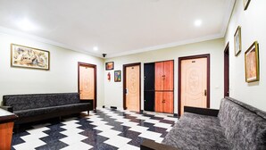 A lobby with a checkered floor, two sofas, and a reception desk. - Deluxe Hotel Okasu Railway Station (Raipur)