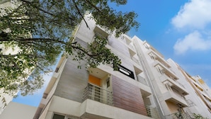 A multi-story building with balconies, a sign indicating a business or office space, and a clear sky. - Classic With Balconyroyal Avenue (Bengaluru)