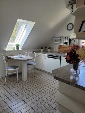 A kitchen with a dining area, a clock, and a window. - Oasis Eichelbachtal (Bad Grund (Harz))