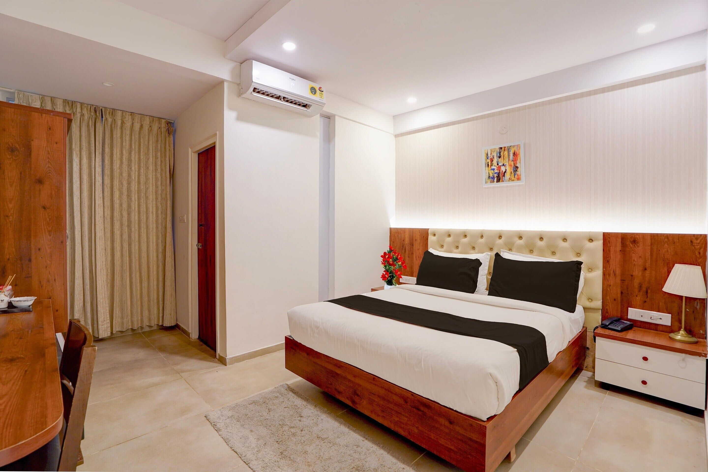 A modern bedroom with a large bed, bedside table, and an air conditioning unit.