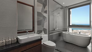 A modern bathroom with a freestanding bathtub, a glass-enclosed shower, a large mirror, and a view of the city. - Villa Nha Trang Ocean Front Luxury Abogo (Nam Nha Trang)