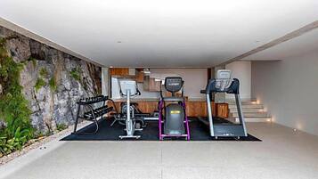 Un gimnasio en casa con cintas de correr, una bicicleta estática y un banco de pesas.