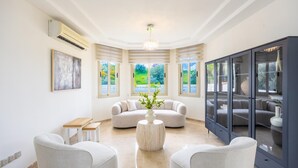 Ein modernes Wohnzimmer mit einer Couch, Sesseln, einem Couchtisch und einem Schrank.