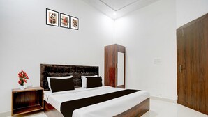 Ein Schlafzimmer mit einem hölzernen Bettgestell, einem Nachttisch mit Blumenvase und einem Kleiderschrank.