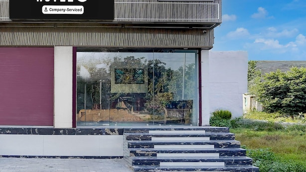 Ein modernes Hotel mit Glasfassade, einer firmenbeschilderung und einer Treppe aus Marmor, die zum Eingang führt.