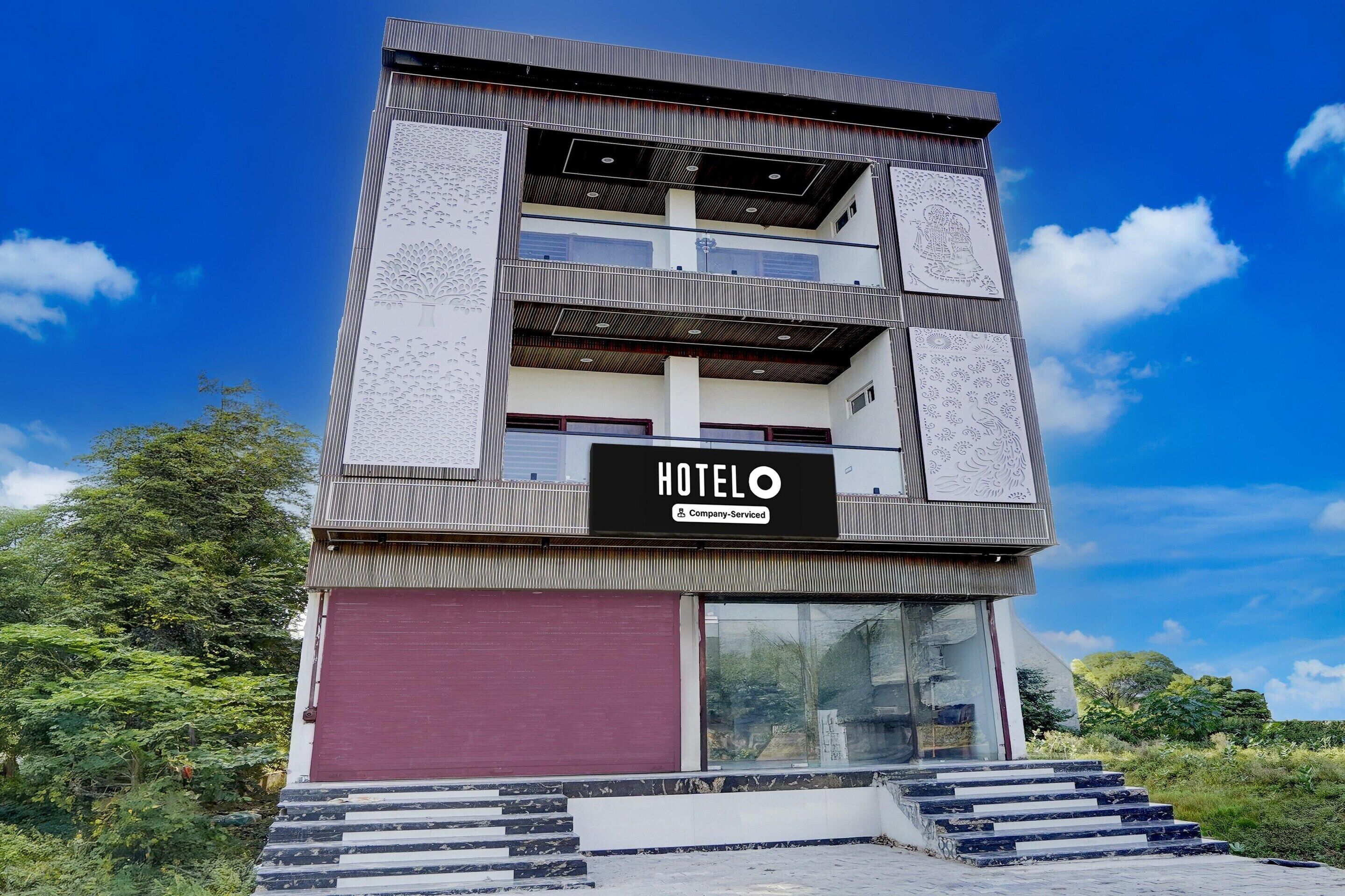 A multi-story hotel with a prominent 'HOTELO' sign, a red door, and a staircase leading to the entrance.