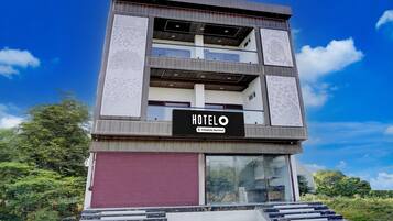 A multi-story hotel with a prominent 'HOTELO' sign, a red door, and a staircase leading to the entrance.