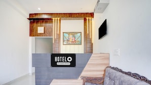 Ein Hotel-Empfangsbereich mit einem Holzbüro, einer Uhr, einem gerahmten Bild und einem Sofa.