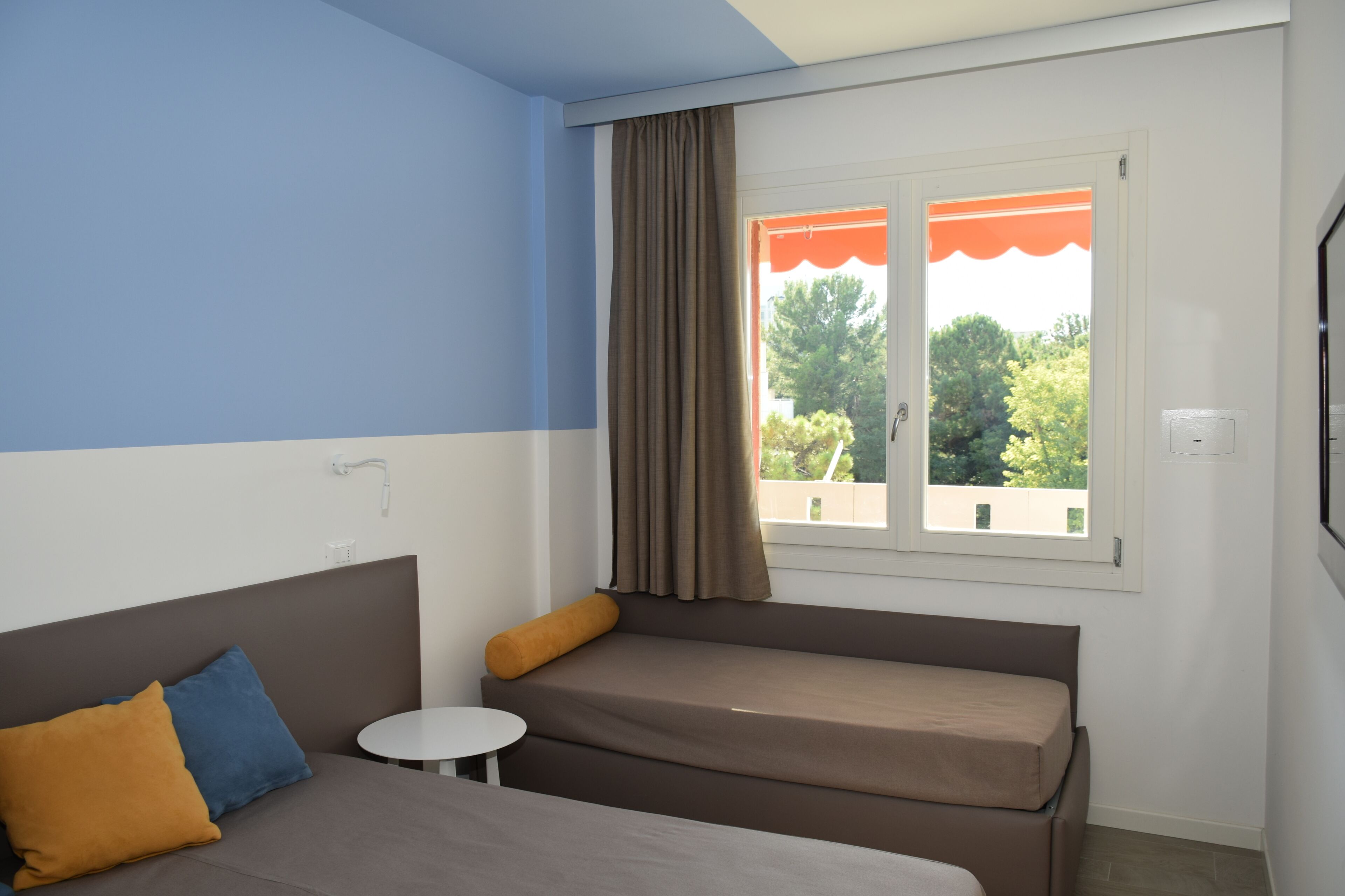 Una habitación con cama, sofá, una mesita y ventana con cortinas.