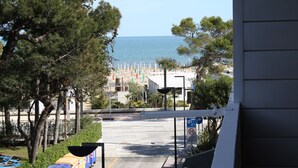 Vista de una playa con sombrillas y sillas de descanso, una carretera que conduce a la playa y una señal de límite de velocidad.