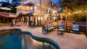 Uma casa de dois andares com piscina, área de estar externa e luzes de Natal.