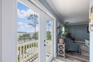 A room with a view of the water, a balcony with a railing, a potted plant, and a small table with a cushion. - Pool + Waterfront + Boat lift (Navarre)