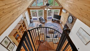 A spacious loft with a wooden interior, a staircase, a seating area with a TV, and large windows offering a view of the outdoors. - Blue Ridge Retreat w/ Private Trail (Pisgah Forest)
