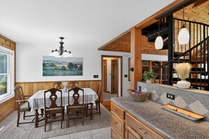 Ein Essbereich mit Holztisch und Stühlen, einer Kristallleuchter und einem Gemälde an der Wand.