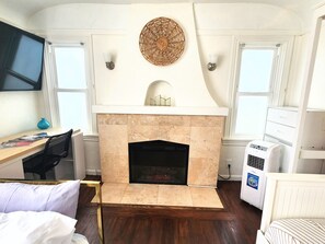 Une pièce avec une cheminée, un bureau, une chaise et un lit.