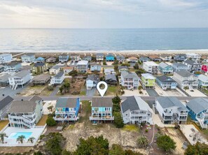 A coastal residential area with multiple two-story houses, a beach in the background, and a clear sky. - Times Like These / 256A Brunswick Ave West (Holden Beach)