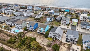 Zona residencial costera con casas, algunas con balcones, y una playa al fondo.