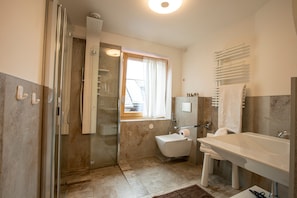 Een badkamer met een douchecabine van glas, een toilet, een wastafel en een bad.