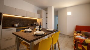 A modern kitchen with a dining area, featuring a wooden table, yellow chairs, and a red sofa. - Chalet 'Apartment 1' with Mountain View, Shared Garden and Wi-Fi (Livigno)
