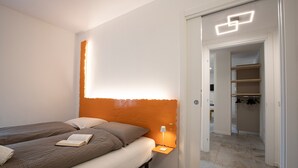 A bedroom with two beds, a nightstand with a lamp, and a closet with hanging clothes. - Chalet 'Apartment 1' with Mountain View, Shared Garden and Wi-Fi (Livigno)