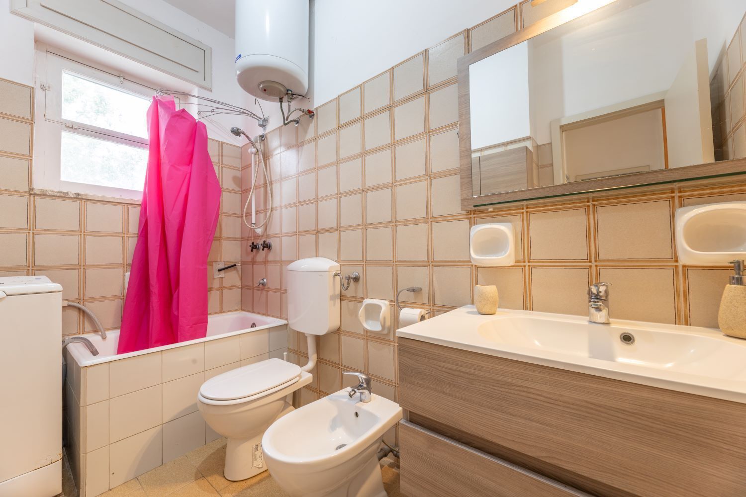Ein Badezimmer mit Badewanne, Toilette, Bidet und einem großen Spiegel.