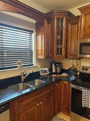Una cocina con armarios de madera, un lavamanos de acero inoxidable, una cafetera y una estufa.