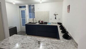 Una cuina moderna amb taulell de marbre, fogó integrat i un rentapeus.