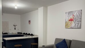 Un saló modern amb un sofà seccional gris, una illa de cuina i un llum de sostre.