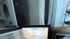 Eine Küche mit einem Edelstahl-Kühlschrank, einer Mikrowelle und einem Holzschrank.
