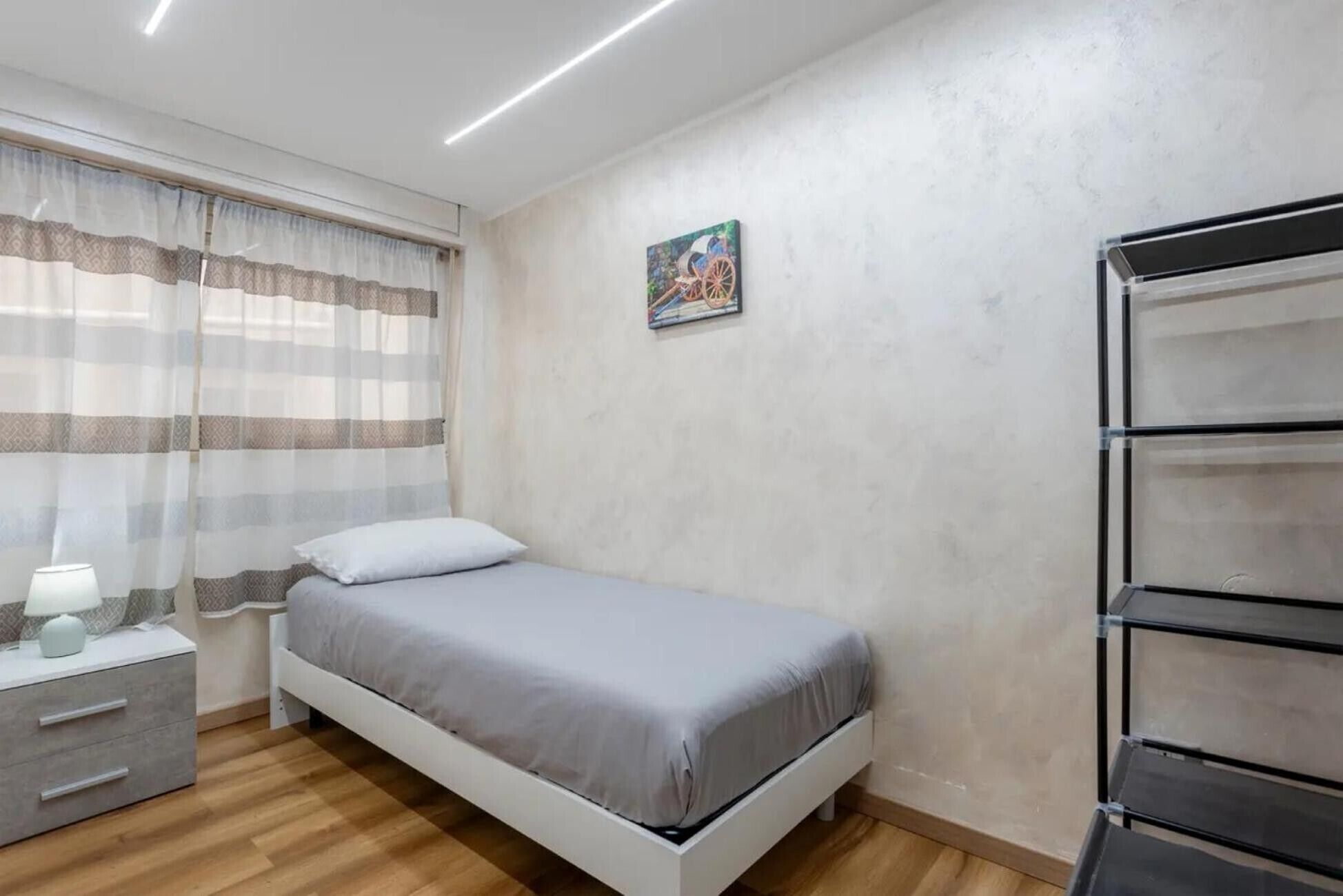 Une chambre à coucher comprenant un lit, une table de chevet, une lampe et une étagère fixée au mur.