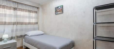 Une chambre à coucher comprenant un lit, une table de chevet, une lampe et une étagère fixée au mur.