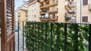 A residential building with multiple balconies, a street view, and a green plant barrier. - 'Oreto Central Station' Apartment with Balcony, Wi-Fi and Air Conditioning (Palermo)