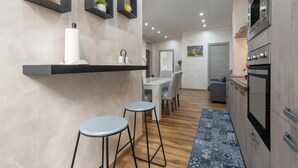 A modern kitchen with built-in appliances, a dining area with a table and chairs, and a small bar area with stools. - 'Oreto Central Station' Apartment with Balcony, Wi-Fi and Air Conditioning (Palermo)