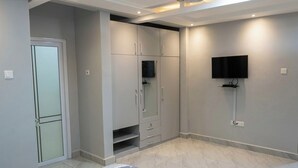 Ein Schlafzimmer mit Bett, Kleiderschrank, Fernseher und einer Tür.