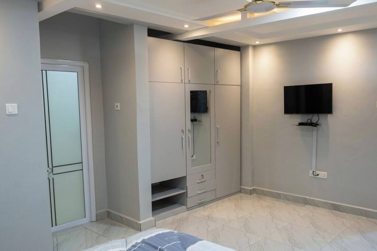 Ein Schlafzimmer mit Bett, Kleiderschrank, Fernseher und einer Tür.