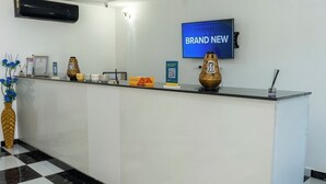 Ein Empfangsschalter mit einem Schild 'BRAND NEW', einem montierten Fernseher und dekorativen Accessoires.