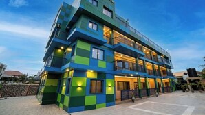 Un hôtel à plusieurs étages, doté de balcons, d’un mur en pierre et d’une cour dallée.