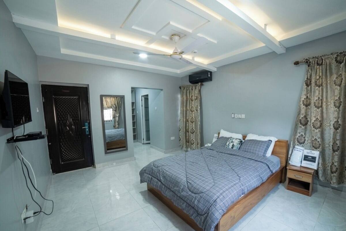 Ein Schlafzimmer mit Bett, Fernseher, Deckenventilator und Tür.