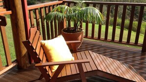 A wooden deck with a bench and a potted plant. - Jacaranda Park Holiday Cottages (Norfolk Island)
