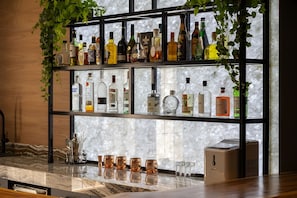 A bar area with shelves of liquor bottles, a marble countertop, and a coffee machine.