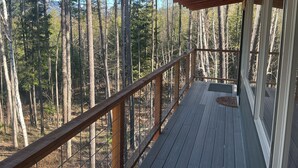 A wooden deck with a railing overlooking a forested area. - Glamping tower north of Columbia Falls views of Whitefish mountain and privacy. (Columbia Falls)