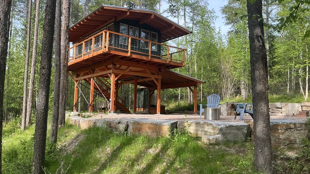A wooden cabin with a balcony, surrounded by trees. - Glamping tower north of Columbia Falls views of Whitefish mountain and privacy. (Columbia Falls)