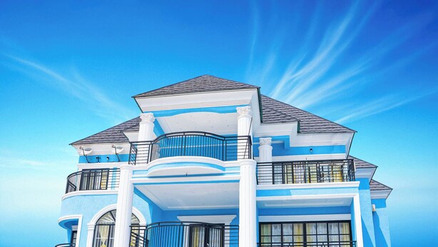 A large, two-story house with a prominent balcony and a symmetrical design.
