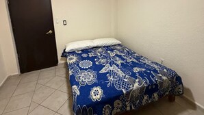 A bedroom with a bed, a ceiling fan, a door, and tiled flooring. - Beachfront Apartment : Caleta Beach + Free Parking (Acapulco de Juárez)