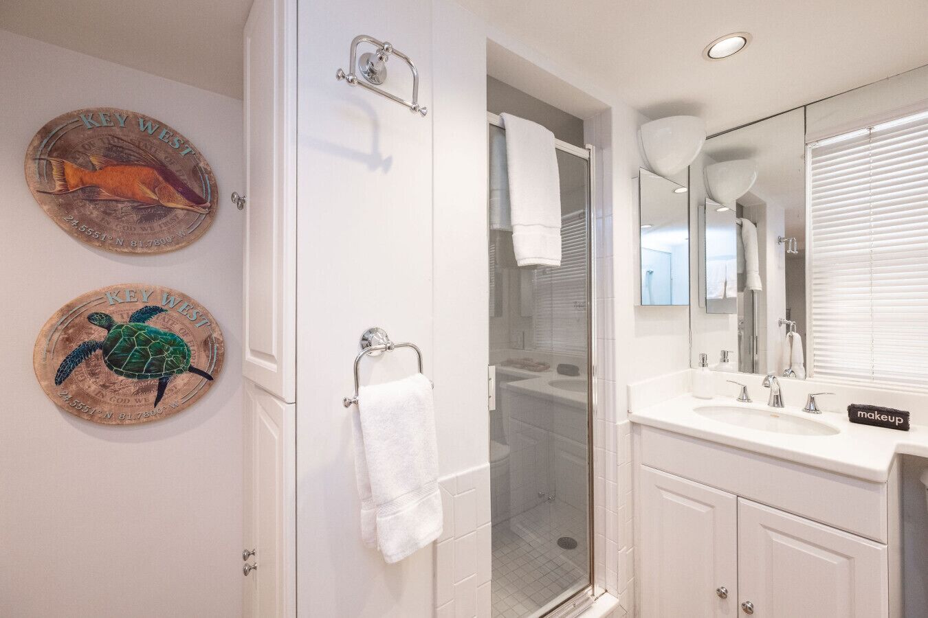 Un baño con ducha, un lavabo, un espejo y dos platos decorativos en la pared.
