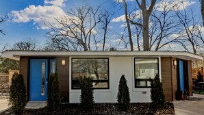 Un bâtiment moderne de plain-pied, doté d’une porte bleue, de grandes fenêtres et d’un petit espace porche.