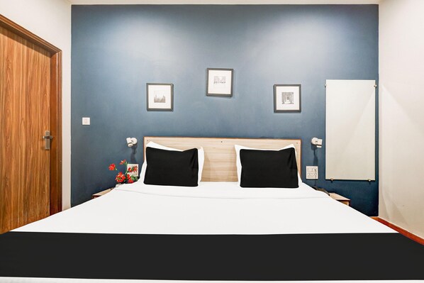 A bedroom with a bed, a wooden door, and a wall with framed pictures.