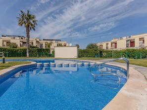 Une piscine dotée d’une plage carrelée, entourée d’une clôture et située à côté d’une rangée d’immeubles d’appartements.