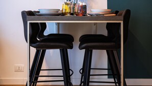 A dining area with a table, two chairs, a vase with flowers, and a painting on the wall. - Glam Turin Apartment, in the heart of San Salvario, a stone's throw from downtown (Torino)