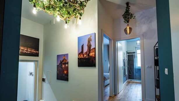 A hallway with wooden flooring, a bench, and a hanging plant. - Glam Turin Apartment, in the heart of San Salvario, a stone's throw from downtown (Torino)
